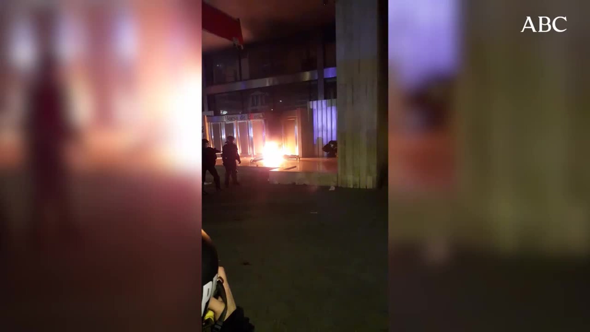 Un vecino intenta apagar una barricada con una papelera y agua de una fuente