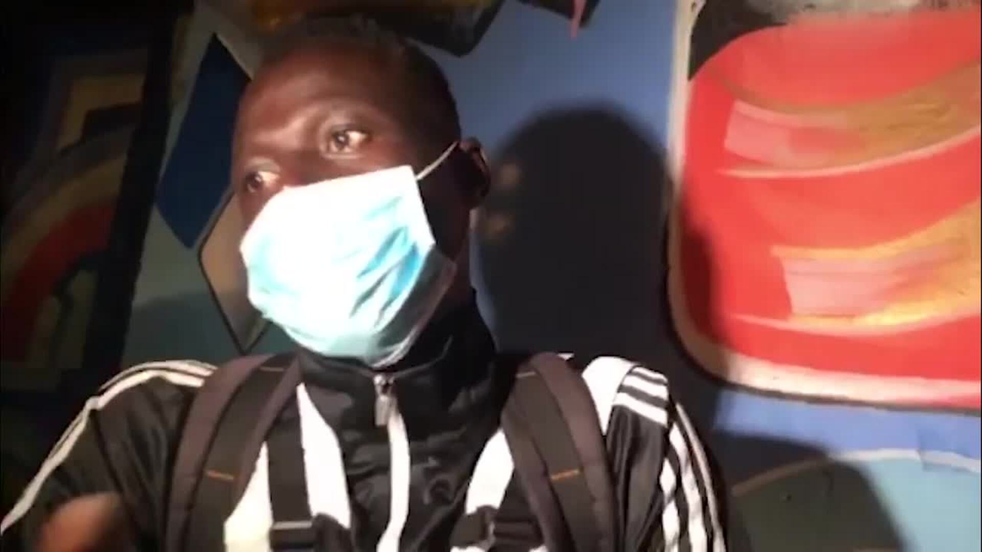 Jacob Ndow cuenta y canta su historia delante de un pequeño mural