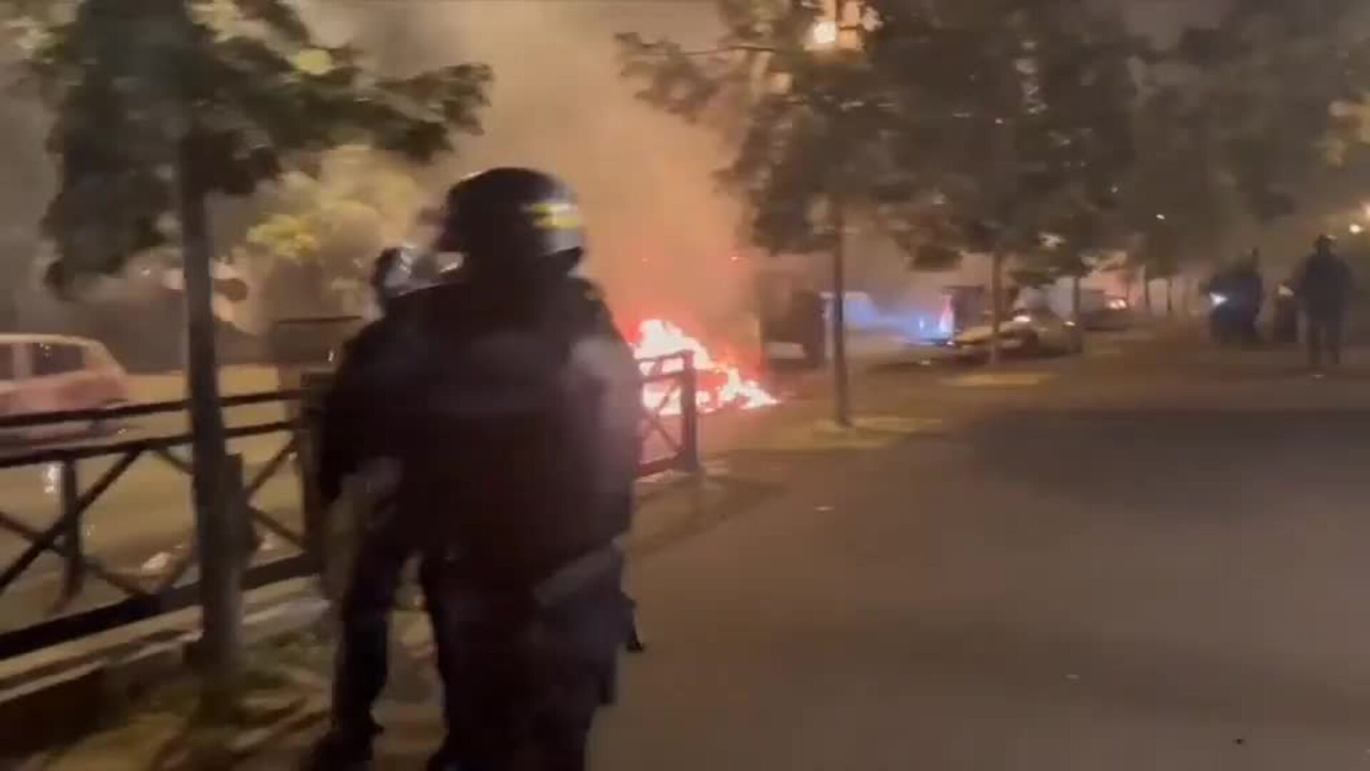Policías antidisturbios franceses caminan junto a un vehículo boca abajo durante el quinto día de protestas