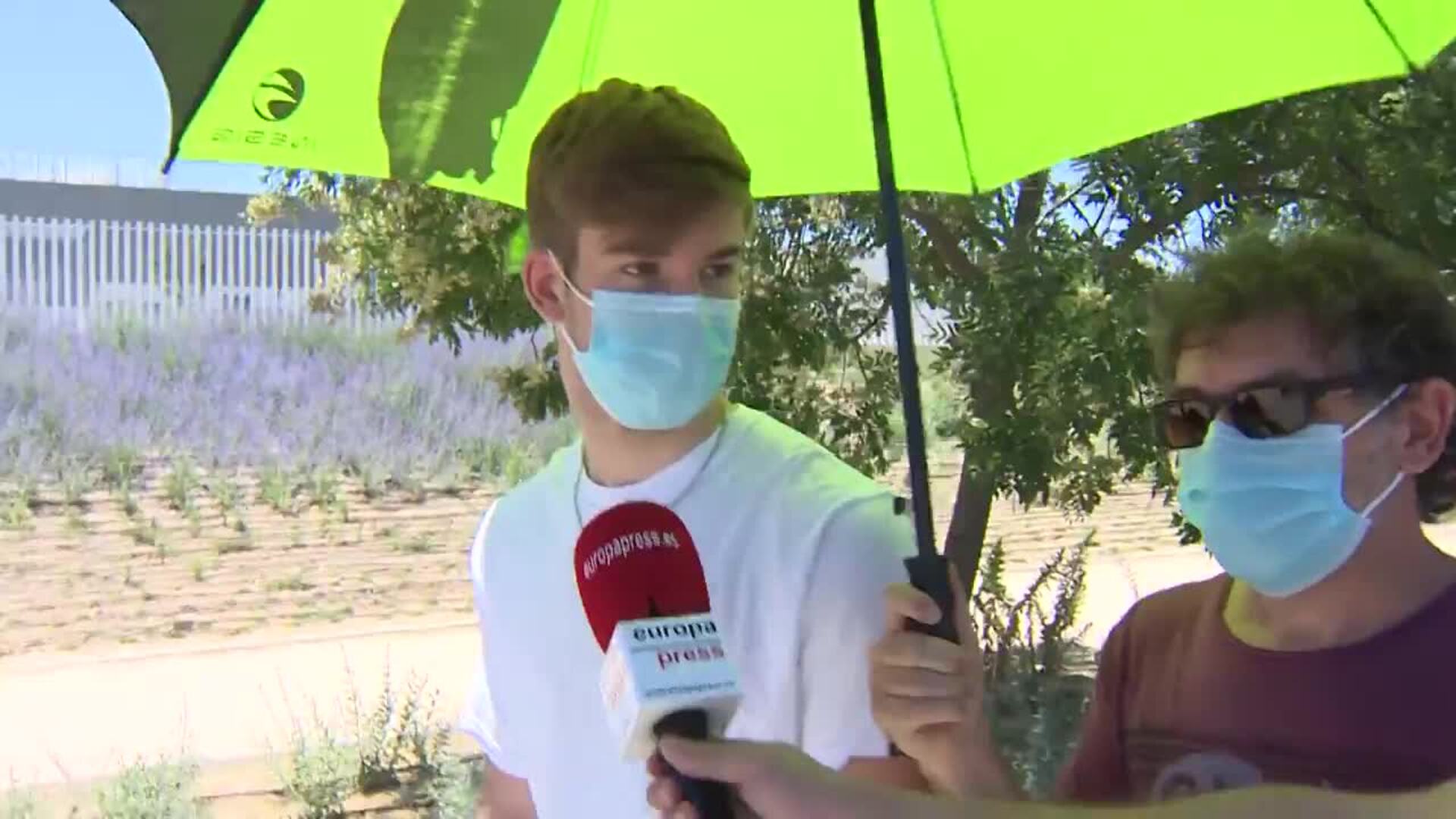 Madrileños se refugian del calor bajo el paraguas mientras esperan ser vacunados