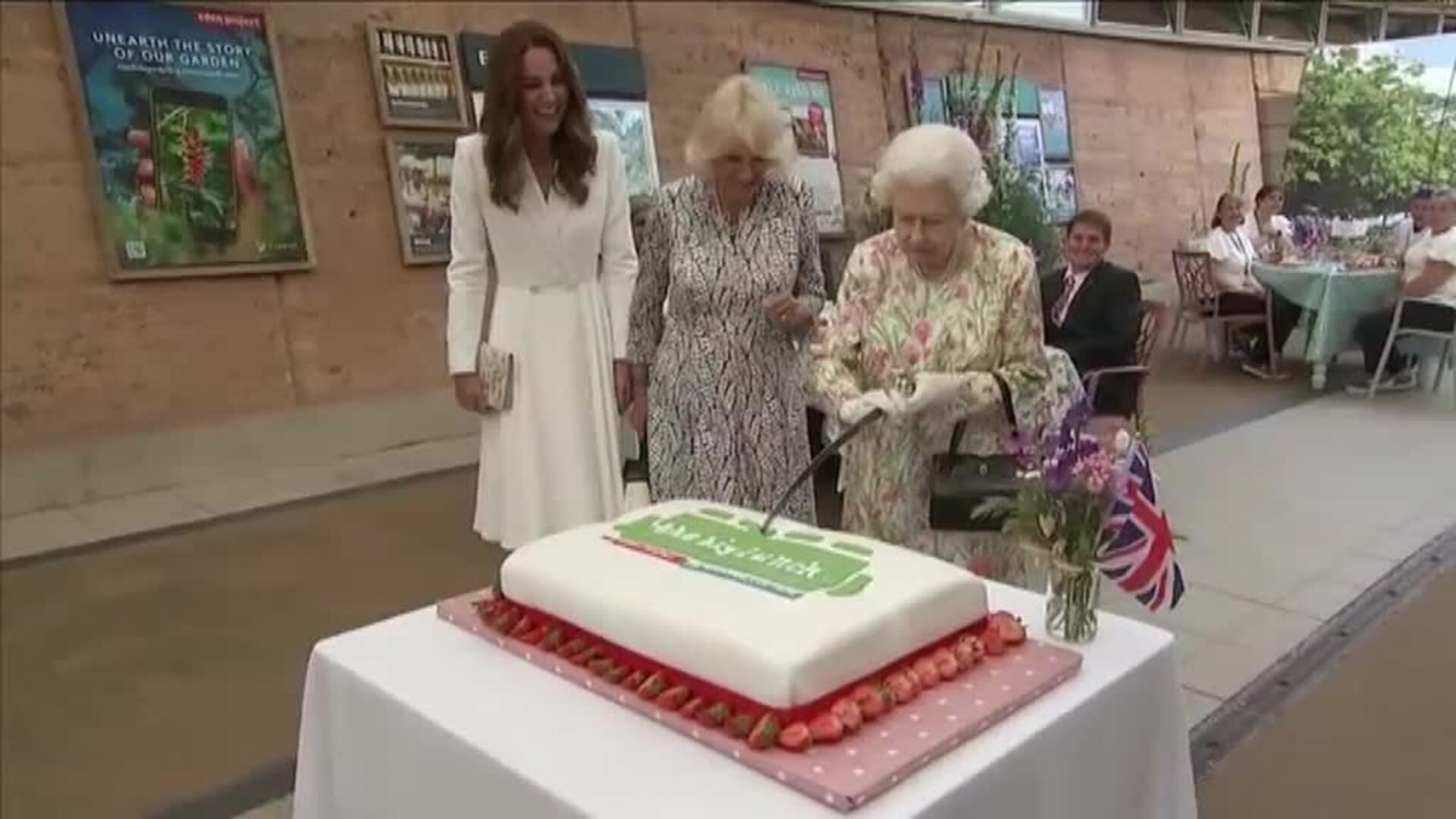 La reina Isabell II corta una gran tarta con una espada en un evento solidario en Reino Unido