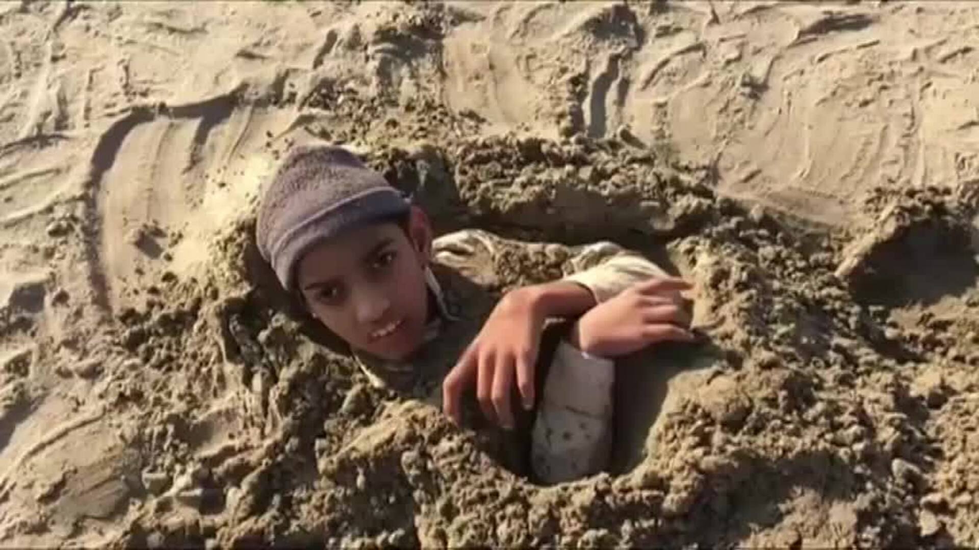 Varios hombres se entierran en una playa de Pakistán durante el eclipse solar