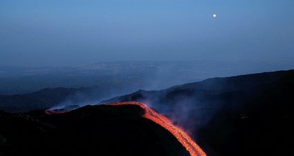 Orange lava flows stream from Mount Etna