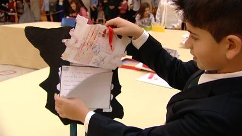 Don Felipe contempla el trabajo del niño Izán Rilova, de Gijón, en presencia de su profesora y del presidente de la Fundación Institucional Española, Rafael Guardans
